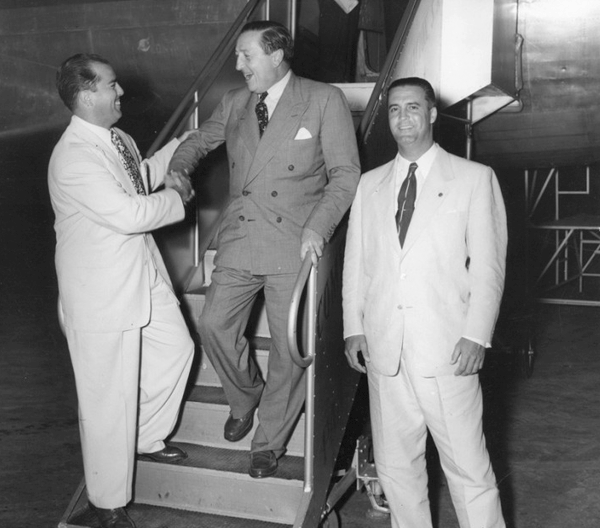 Cornelius Vander Starr disembarking a plane and being greeted in Cuba