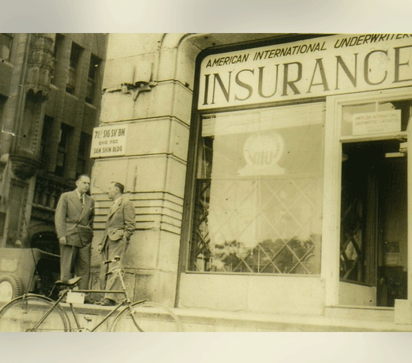 Two men talking to each other in front of an American International Underwriters office